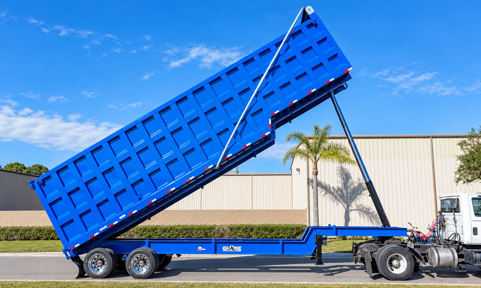 Blue Globe demolition dump trailer raised for unloading with hydraulic hoist extended